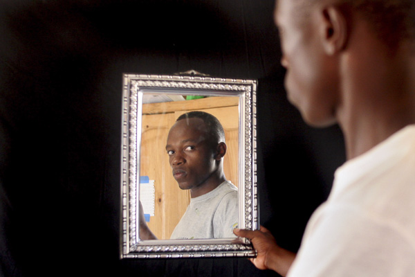 Self-portrait by Joshua Munyaburanga. Joshua calls this image "Two Brothers" as the boy on the right side of the frame is his brother, Sustain, while the face in the mirror is his own.