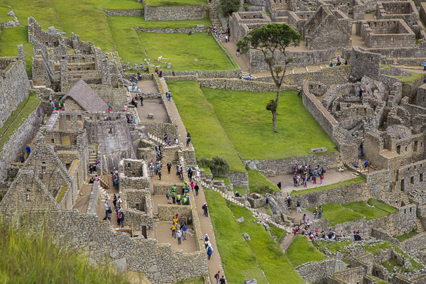  Tourists explore Machu Pichu's stone structure. The number of daily tourists who visit the site relatively unresricted has put the Machu Pichu on the endangered archeological site and the Peruvian government is considering tighter restrictions. 